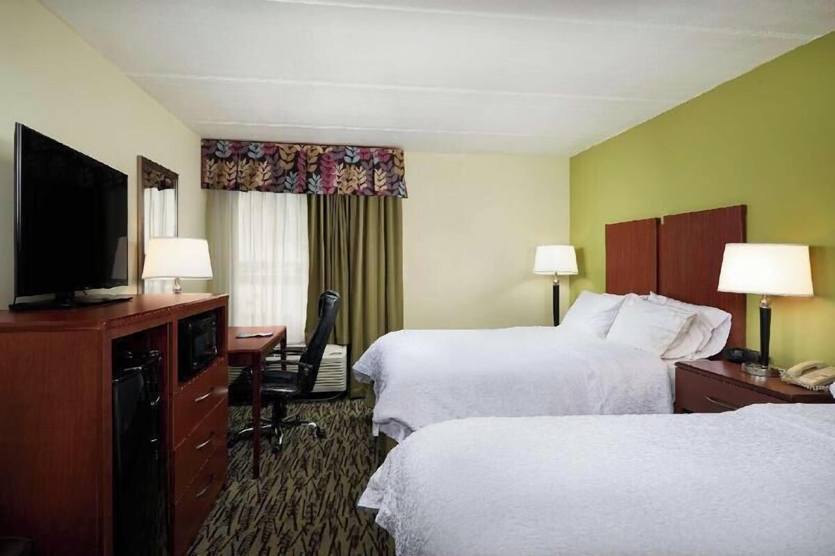 Habitación de hotel con dos camas, un escritorio, televisor y minibar.