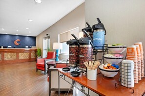 A hotel reception area with a modern design, including a reception desk, seating area, and a coffee station with various coffee beans and a water dispenser. - Comfort Inn & Suites North Greenfield (Greenfield)