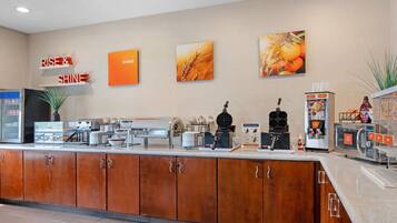 A modern kitchen area with a coffee station, a microwave, and a refrigerator.