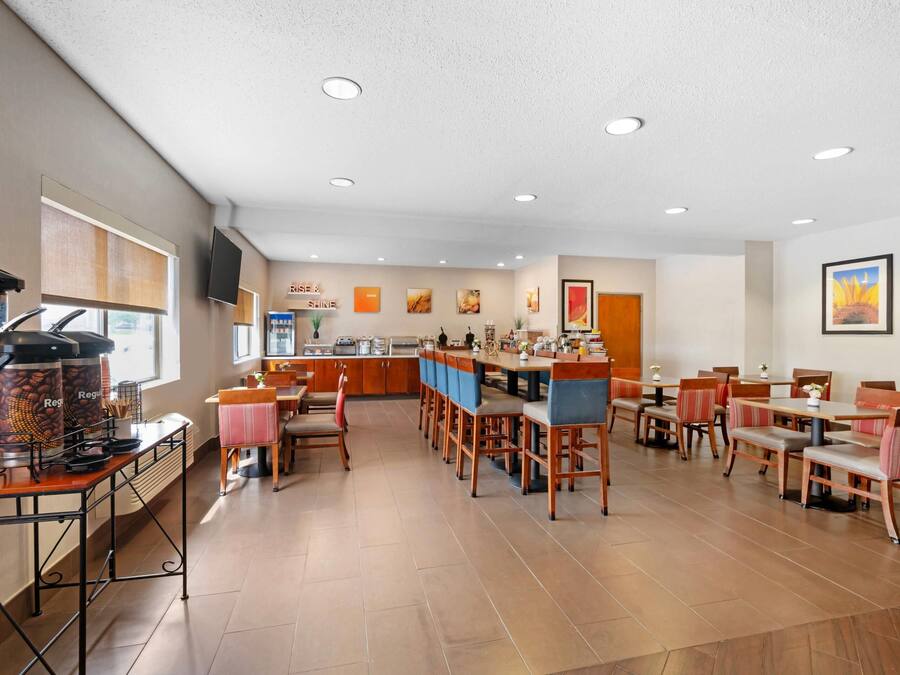 A restaurant with a bar area, multiple tables and chairs, and a kitchen in the background.