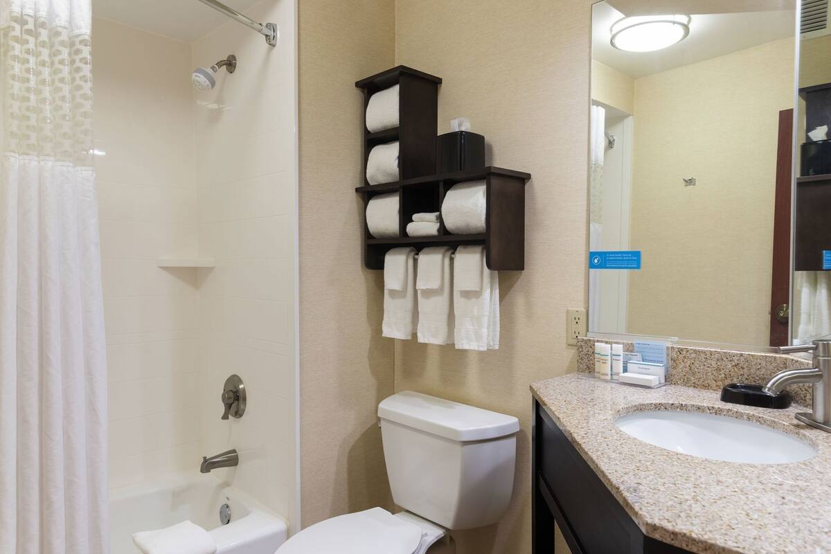 A bathroom with a shower, toilet, sink, and towel rack.