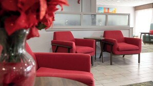 A modern lobby with red chairs, a wooden table, and a vase with red flowers. - Hampton Inn Kent/Akron Area (Kent)