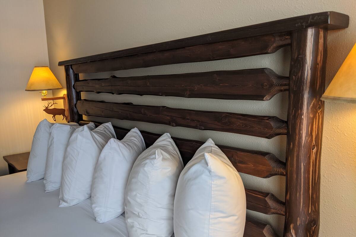 Un lit avec une tête de lit en bois et des oreillers blancs.