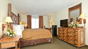 Quarto de hotel com uma cama, uma escrivaninha, uma televisão e um armário.