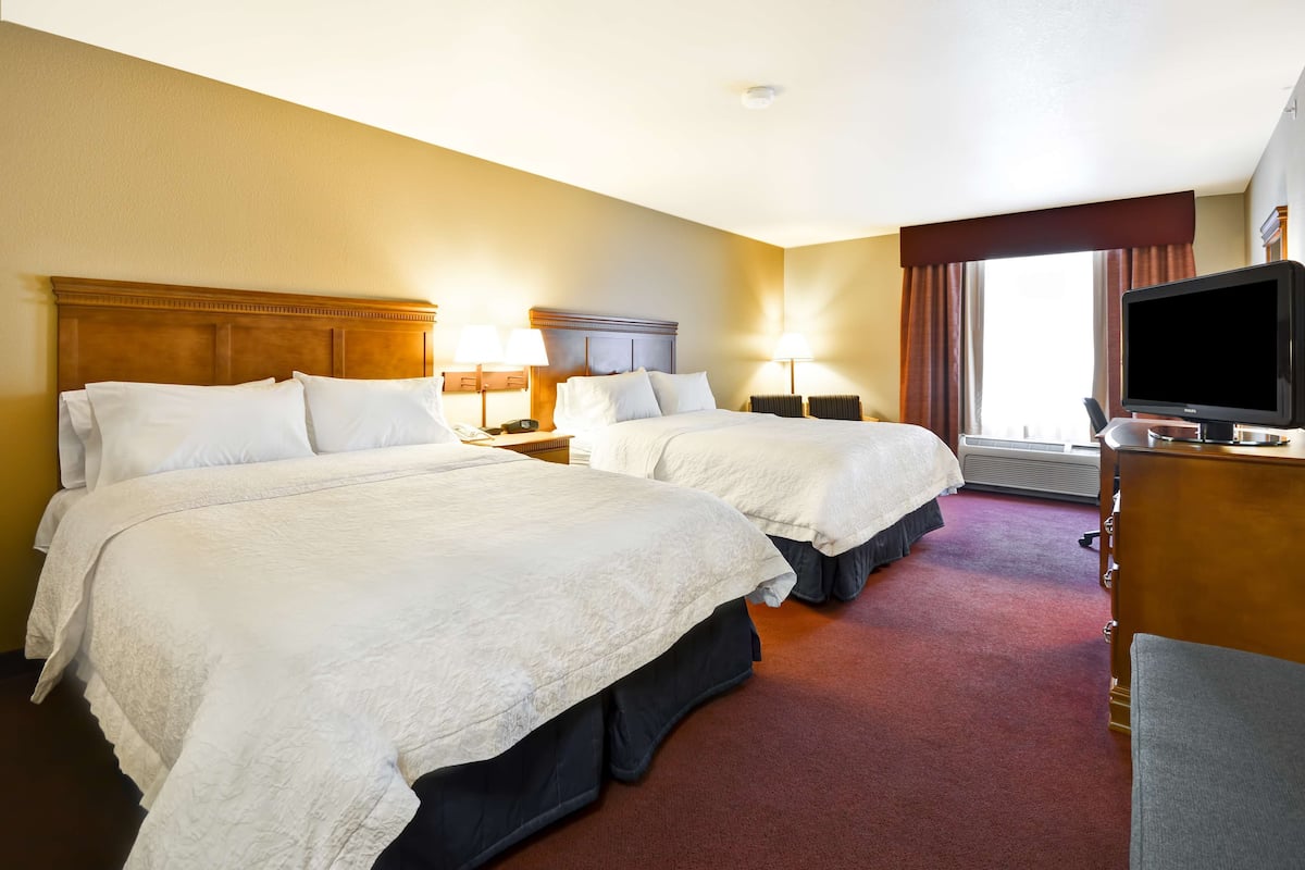 A hotel room with two beds, a television, and a desk.