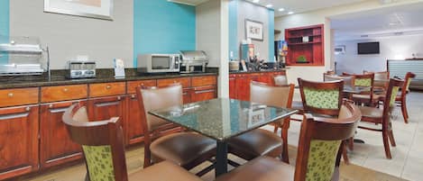 Un restaurante con armarios de madera, una barra y una zona de estar con sillas y una mesa.