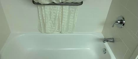 A standard bathtub with a shower faucet and a curtain rod.