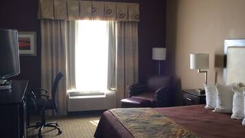 A hotel room with a bed, desk, chair, and a television.