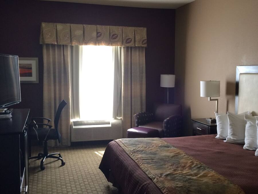 A hotel room with a bed, desk, chair, and a television.