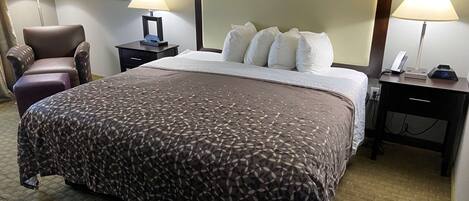 Una habitación de hotel con una cama grande, dos mesitas de noche, una silla y una lámpara a cada lado.