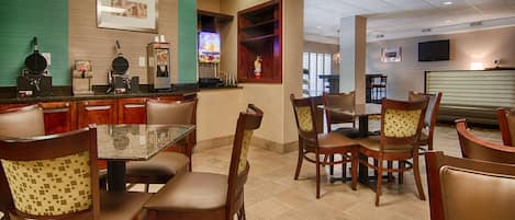 A restaurant with a bar area, wooden chairs, and a television screen.