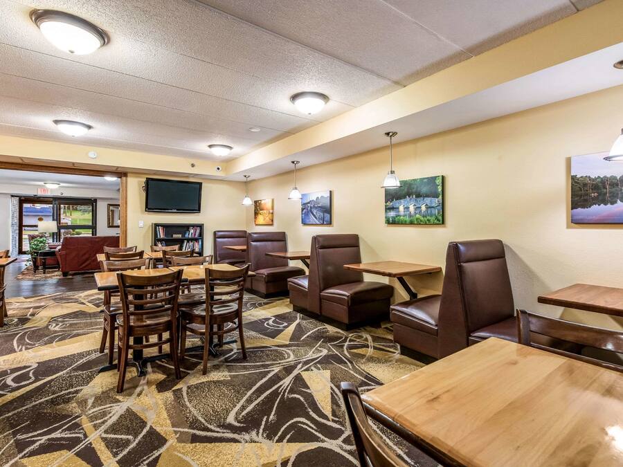 A hotel lobby with seating areas, a TV mounted on the wall, and artwork on the walls.