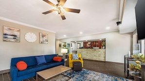 A modern living room with a blue sofa, a yellow armchair, a coffee table, and a ceiling fan. - Comfort Suites Omaha East-Council Bluffs (Council Bluffs)