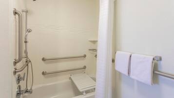 Un baño con bañera, barras de apoyo, ducha y perchero para toallas.
