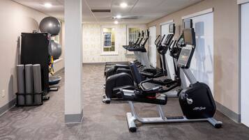 A gym with treadmills, stationary bikes, and exercise balls.