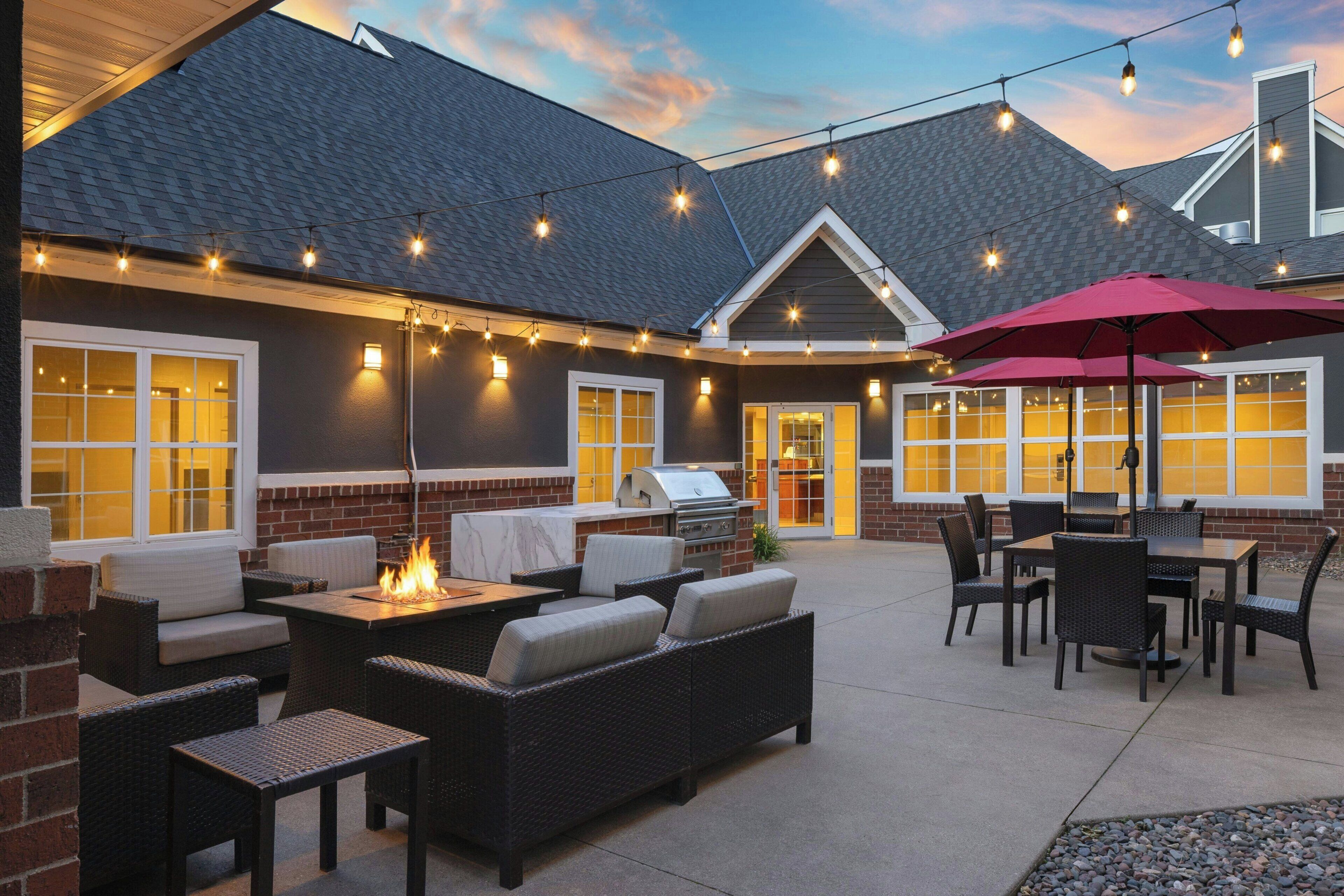 An outdoor patio area with seating, a barbecue grill, and string lights.