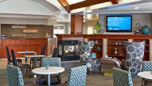 A hotel lobby with a fireplace, seating area, television, and wooden paneling. - Residence Inn by Marriott Minneapolis St. Paul/Roseville (Roseville)