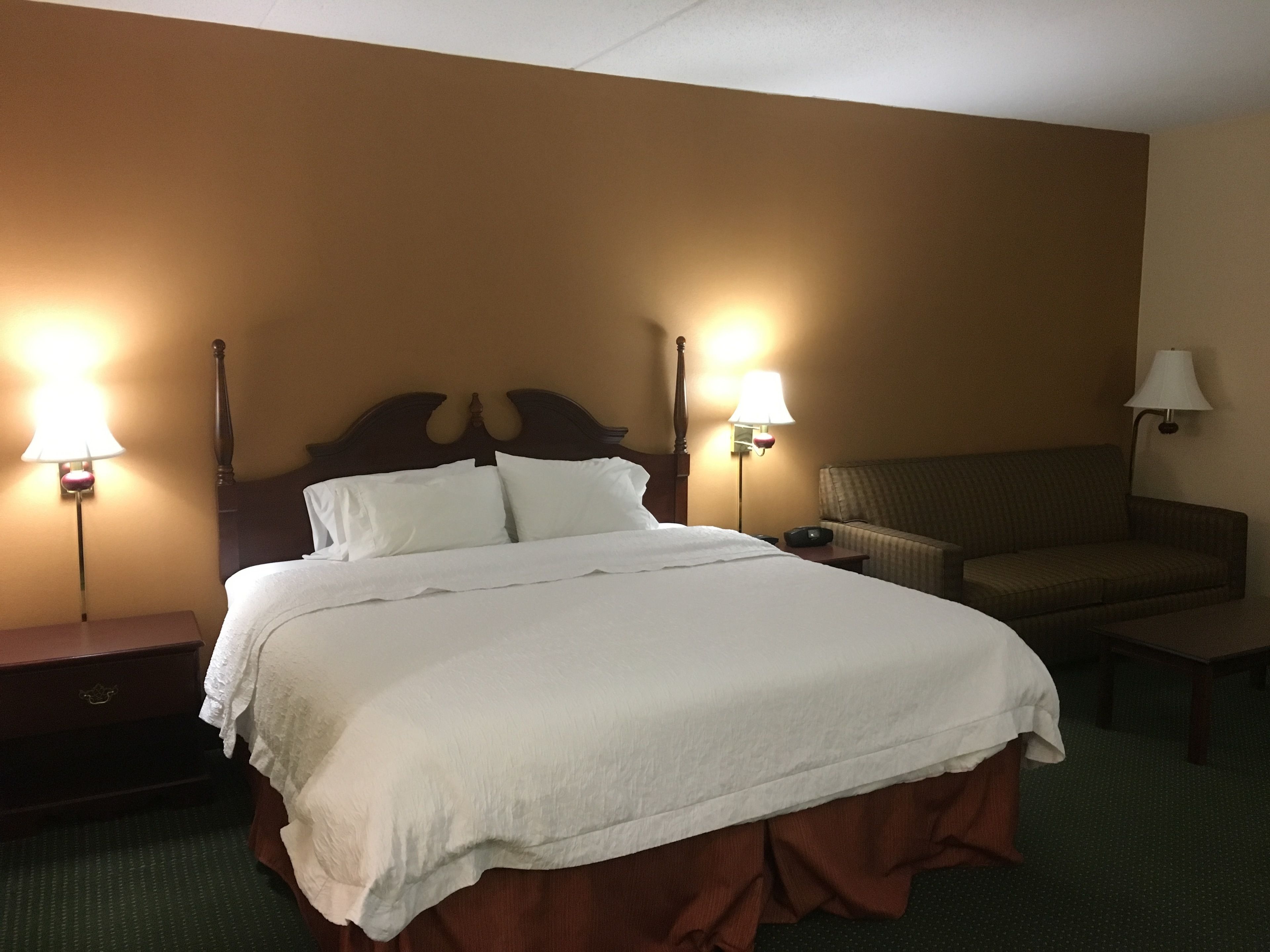 Een hotelkamer met een groot bed, twee bedlampen, een stoel en een kleine tafel.