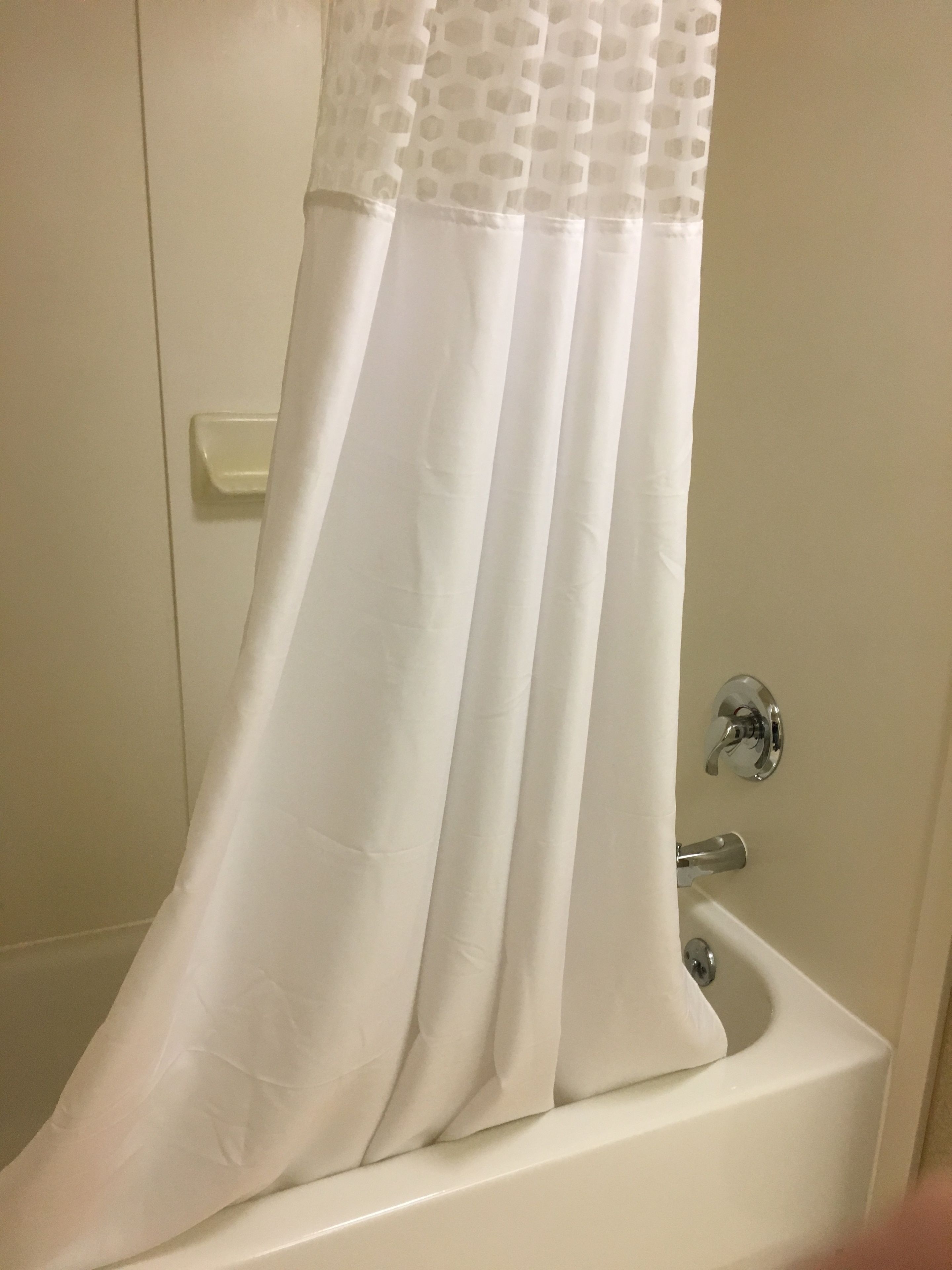 A white bathtub with a shower curtain featuring a hexagonal pattern.