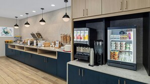 Una barra de desayuno moderna con una máquina de café, un refrigerador exhibidor y diferentes alimentos.