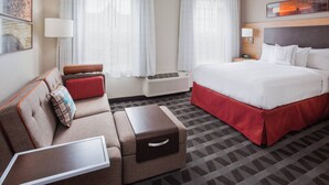 Una habitación de hotel con cama, sofá, mesita auxiliar y lámpara.