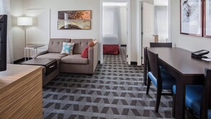 Una habitación de hotel con sofá, escritorio, lámpara y cama.