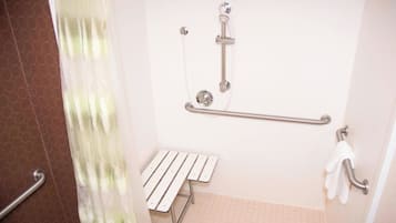 Un baño con ducha, barras de apoyo, un banco y un perchero para toallas.