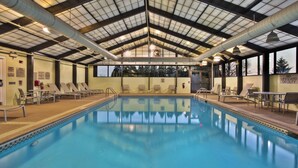 A large indoor swimming pool with clear water, surrounded by lounge chairs and tables, under a high ceiling with visible structural beams and ductwork. - SpringHill Suites by Marriott Chicago Naperville/Warrenville (Warrenville)