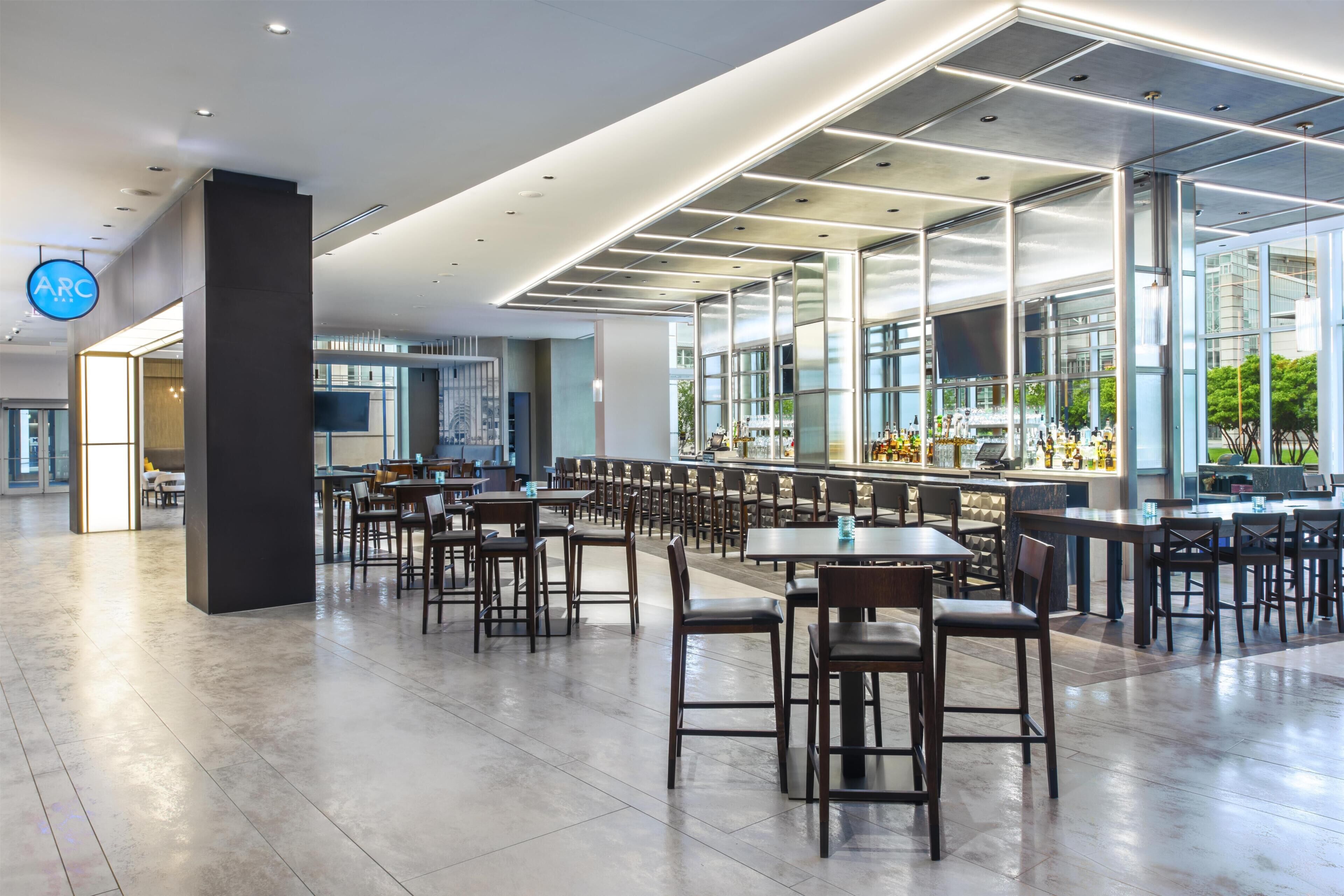Un espace intérieur spacieux, doté de nombreuses tables et chaises, d’un bar et de grandes fenêtres laissant entrer la lumière naturelle.