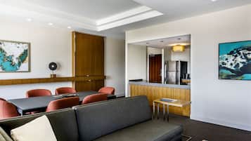 A modern hotel room with a dining area, kitchenette, and a sofa.