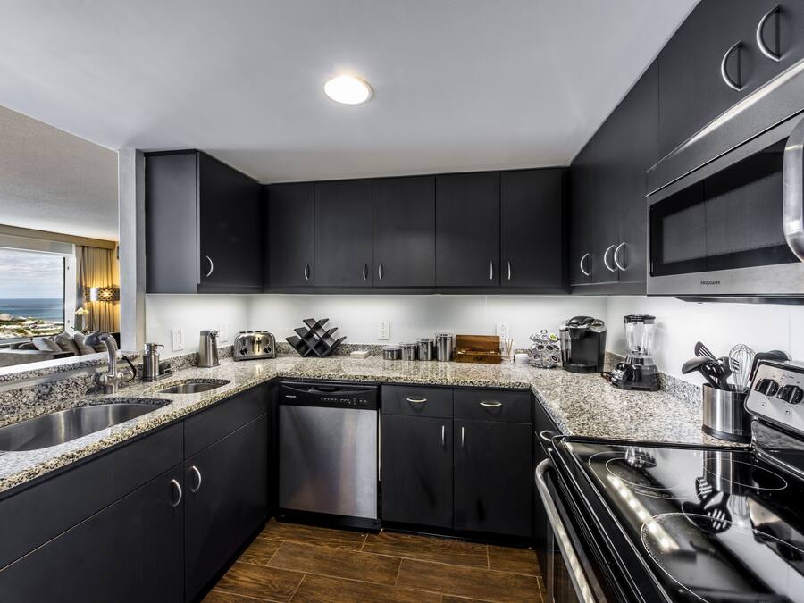 Une cuisine moderne avec des meubles de couleur sombre, des appareils en acier inoxydable et des plans de travail en granit.