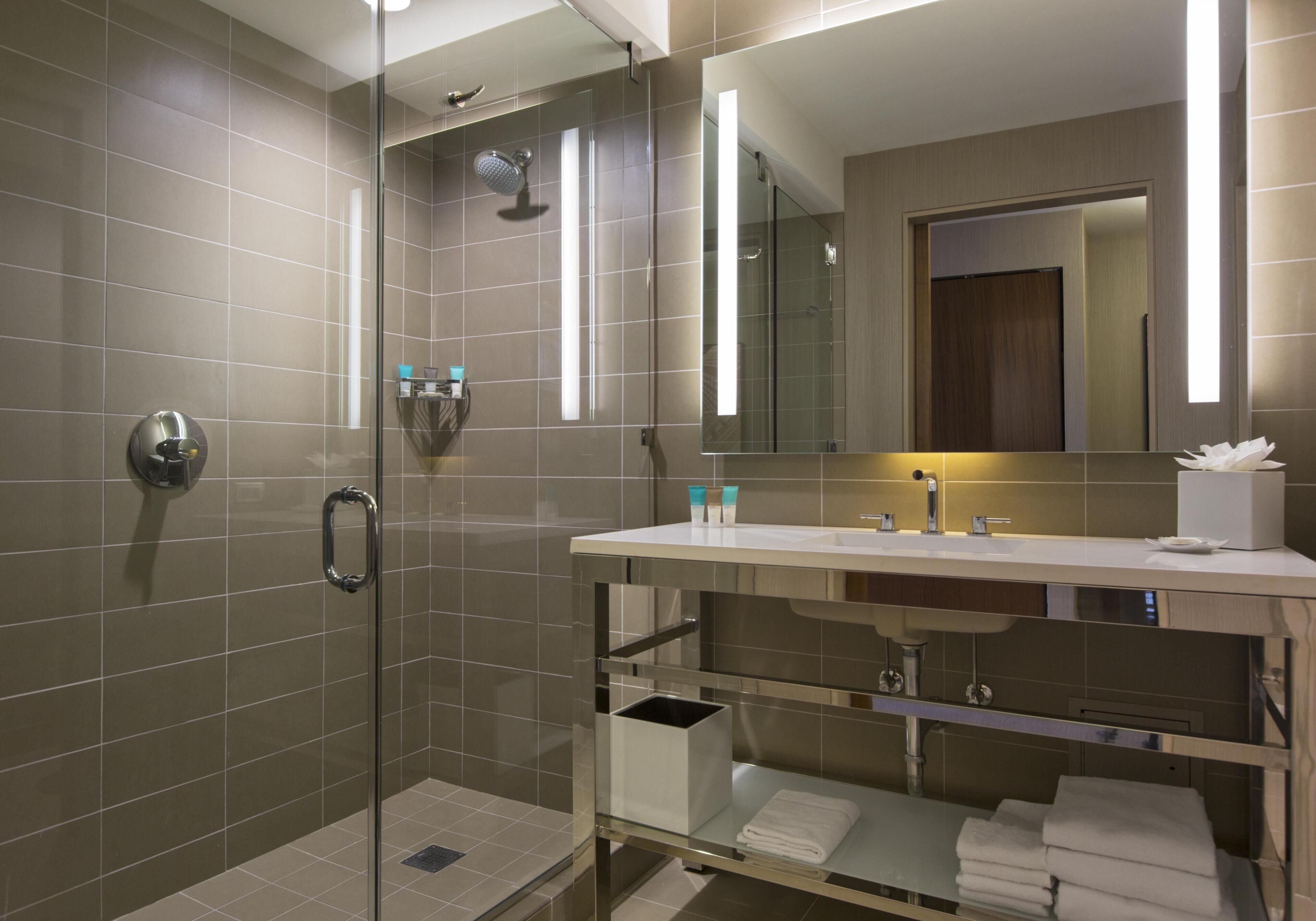 A modern bathroom with a glass-enclosed shower, a vanity with a mirror, and a towel rack.