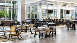 A spacious indoor area with multiple tables and chairs, large windows, and a bar area. - Hyatt Regency McCormick Place Chicago    (Chicago)