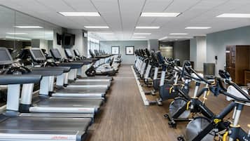 Un gimnasio con cintas de correr, bicicletas estáticas y elípticas dispuestas en filas.