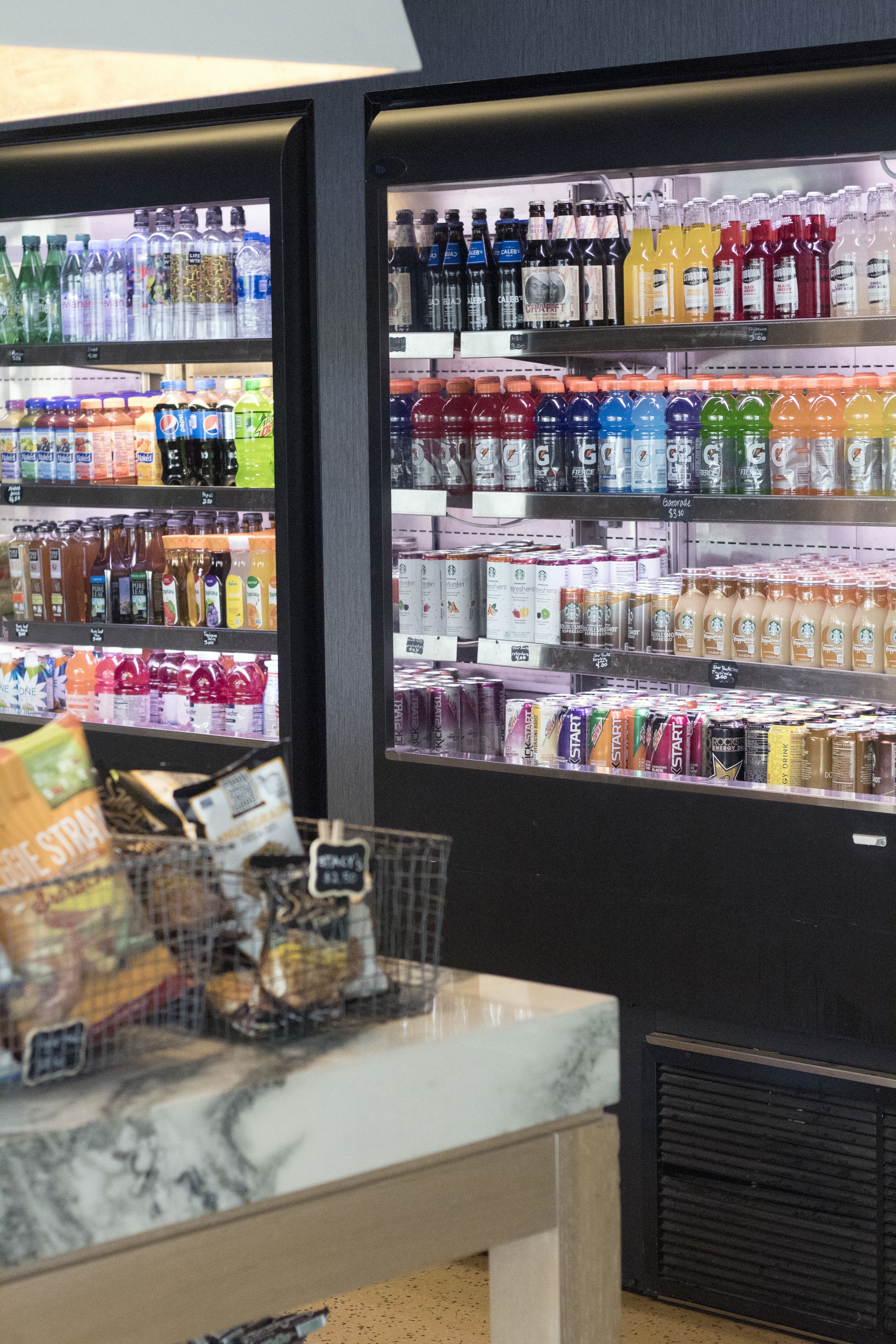Un expositor refrigerado lleno de diferentes bebidas y aperitivos.
