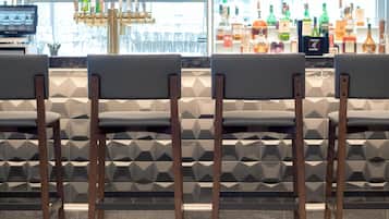 Eine Bar mit vier Stühlen, einer Theke und einer Auswahl an Spirituosenflaschen.