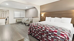 Ein Hotelzimmer mit einem großen Bett, einem Schreibtisch, einem Sessel und einem Schminktisch mit Spiegel.