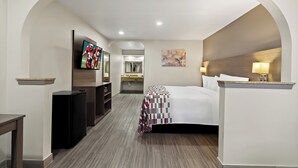 Habitación de hotel con cama, televisión, escritorio y baño al fondo.