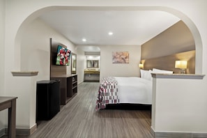 Une chambre d’hôtel avec un lit, une télévision, un bureau et une salle de bain à l’arrière-plan.