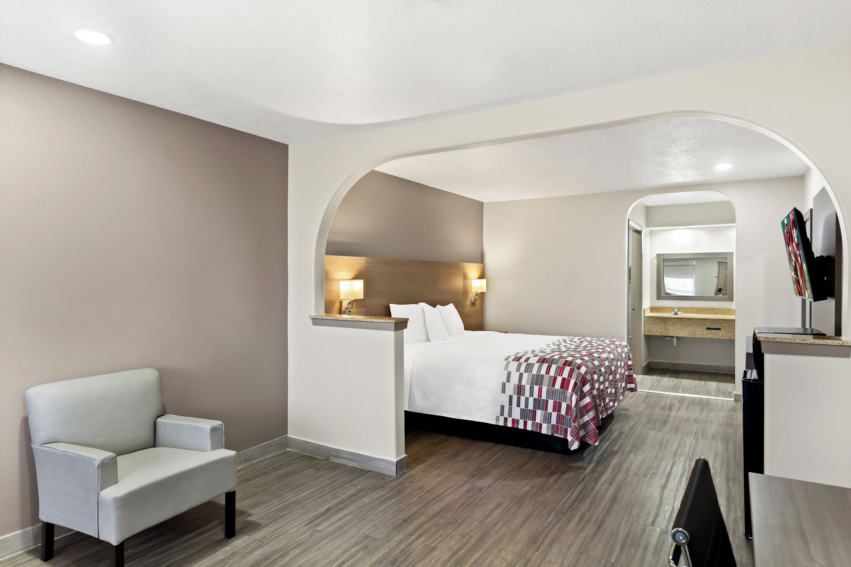 A hotel room with a bed, a seating area, a desk, and a bathroom.