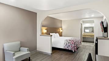 A hotel room with a bed, a seating area, a desk, and a bathroom.