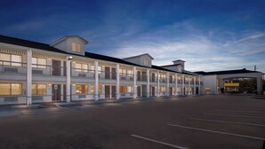 Ein mehrstöckiges Hotel mit Parkplatz und Tankstelle.