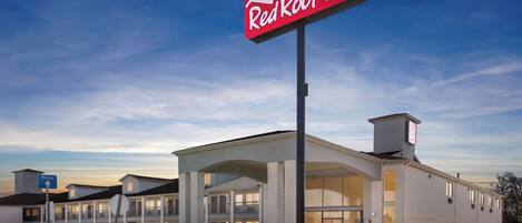 A Red Roof Inn with a large sign, a covered parking area, and a well-maintained lawn.