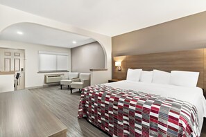 A hotel room with a large bed, a desk, a chair, and a vanity with a mirror. - Red Roof Inn Stafford, TX (Stafford)