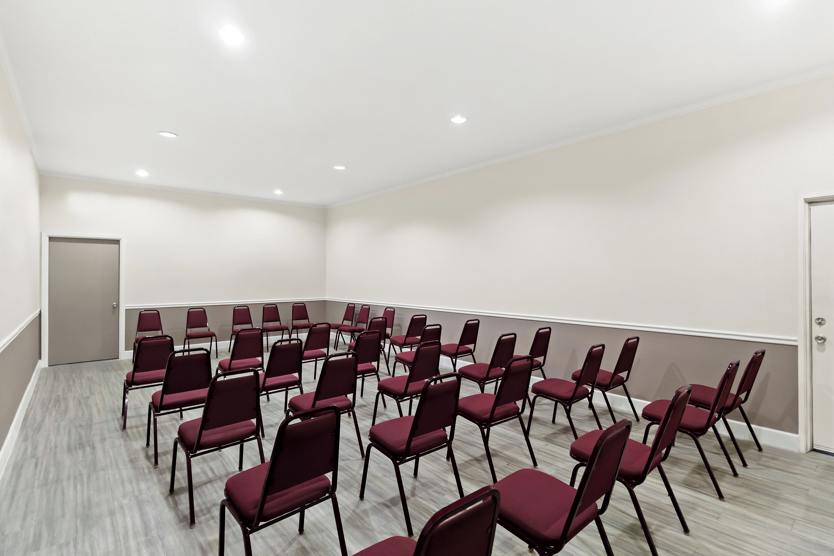 A conference room with rows of chairs and a door.