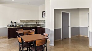 Una cocina moderna con encimeras de granito, muebles oscuros y un comedor con mesas y sillas de madera.