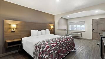 A modern hotel room with a large bed, bedside lamps, a wooden headboard, a window with a view, and a built-in heater.