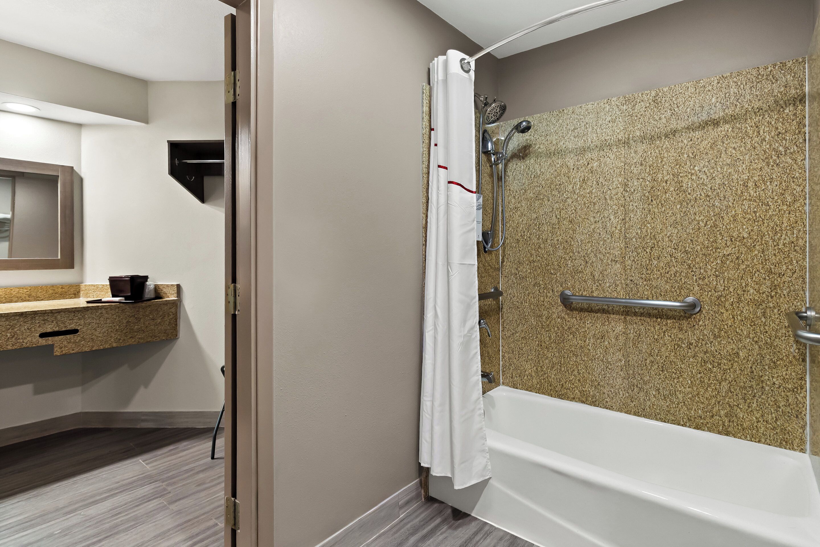 A modern bathroom with a shower, a bathtub, a vanity with a mirror, and a towel rack.