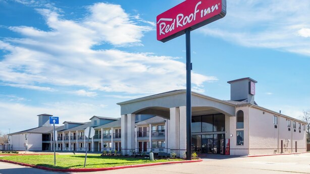 Ein Red Roof Inn mit blauem Himmel und einem Schild, das einen Auslieferungsbereich kennzeichnet.
