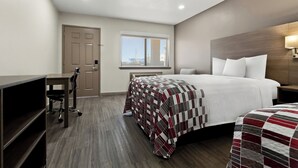 Habitación de hotel con cama, escritorio y silla. Se ve una ventana con vista al exterior.